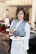 Portrait of smiling waitress holding desserts in restaurant