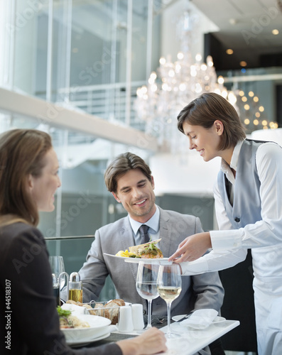 Photo: Waitress serving food to couple in restaurant Waitress serving food to couple in restaurant