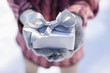 Close up of hands cupping Christmas gift with silver ribbon