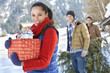 Portrait of friends with fresh cut Christmas tree and gifts in snow