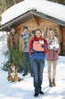 Photo: Portrait of smiling couples and dog with fresh cut Christmas tree and gifts in front of cabin Portrait of smiling couples and dog with fresh cut Christmas tree and gifts in front of cabin