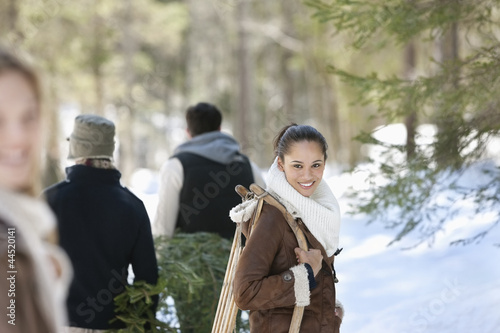 Photo: Friends with fresh cut Christmas tree and sled in snowy woods Friends with fresh cut Christmas tree and sled in snowy woods