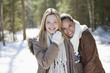 Portrait of smiling friends hugging in snowy woods