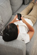 Young woman playing on couch with mobile phone