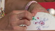 Woman hands doing cross-stitch. A close up of embroidery.