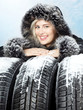 Beautiful woman with winter coat behind snowy winter tyres