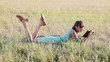 Young woman browsing in Internet with tablet lying on the grass