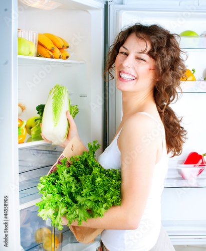 Photo: Beautiful Young Woman near the Refrigerator with healthy food Beautiful Young Woman near the Refrigerator with healthy food