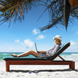 Young woman with a laptop under the palm tree