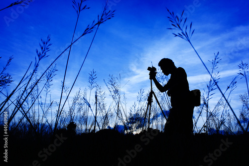 Photo: Silhouette of the photographer on a Grass on a foreground Silhouette of the photographer on a Grass on a foreground