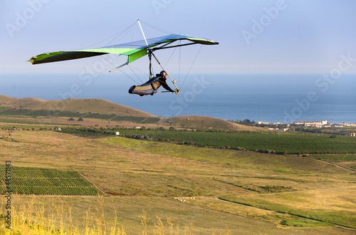 Photo: hand gliding up to yellow green meadow near the sea hand gliding up to yellow green meadow near the sea