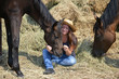 Girl and her horses resting near a haystack