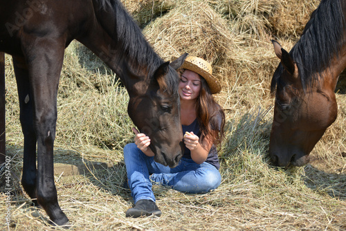 Photo: Girl and her horses resting near a haystack Girl and her horses resting near a haystack