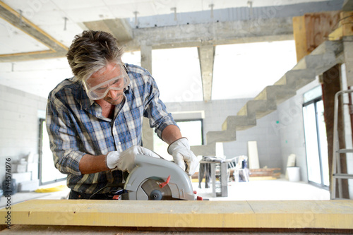 Photo: Man using electric saw inside house under construction Man using electric saw inside house under construction