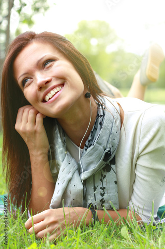 Photo: Beautiful Young Woman with Headphones Outdoors. Enjoying Music Beautiful Young Woman with Headphones Outdoors. Enjoying Music