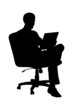 A silhouette of a businessman sitting in office chair and workin