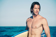 Strong young surf man portrait at the beach with a surfboard.