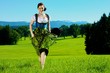 Junge attraktive Frau im Dirndl läuft auf Wiese
