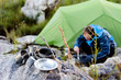 Outdoors man cooking beside his camping tent