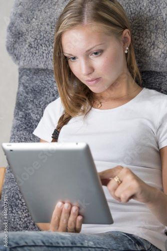 Photo: Young adult female reading on a tablet pc Young adult female reading on a tablet pc