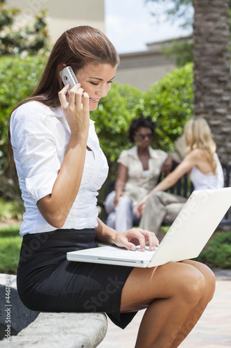 Photo: Young Woman On Cell Phone Using Laptop Computer Young Woman On Cell Phone Using Laptop Computer