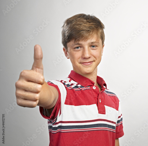 Photo: Happy casual young man showing thumb up and smiling Happy casual young man showing thumb up and smiling