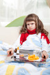 Little sick girl with scarf in bed is taking medicine