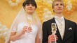 Newly-married couple stands together with champagne glasses
