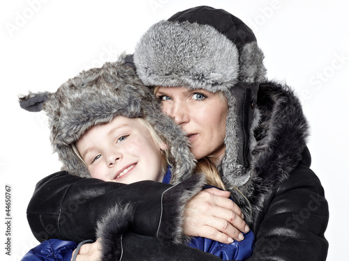 Photo: Mother and daughter in warm winter coats huggle together Mother and daughter in warm winter coats huggle together