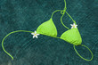 Green bikini floating with pulmeria flowers