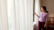 woman draws curtains and opens window