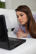 Serious woman using a laptop on a sofa