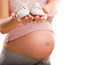 Pregnant woman holding pair of white  shoes for baby (Shallow do