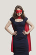 Portrait of a young woman in superhero costume over gray background