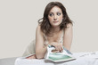 Young woman looking away while ironing shirt over gray background