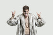 Foto: Portrait of an angry young man making rebellious gestures and sticking out tongue against gray background Portrait of an angry young man making rebellious gestures and sticking out tongue against gray background