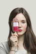 Portrait of young woman with red lips holding ice cream bar against gray background