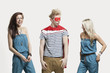 Photo: Young man in superhero costume standing with happy female friends in matching jump suits against gray background Young man in superhero costume standing with happy female friends in matching jump suits against gray background