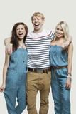 Photo: Portrait of young woman standing with cheerful friends against gray background Portrait of young woman standing with cheerful friends against gray background