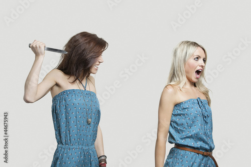 Photo: Friend stabbing young woman in similar jump suits from behind Friend stabbing young woman in similar jump suits from behind