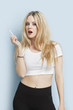 Foto: Portrait of young blond woman holding cigarette against light blue background Portrait of young blond woman holding cigarette against light blue background