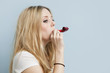 Young woman with party blower against light blue background