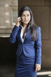 Young Indian businesswoman looking away while using cell phone