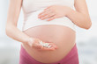 belly of pregnant woman and vitamin pills in the hand