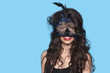 Portrait of a young woman wearing exotic eye mask over blue background