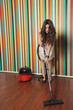 Young woman cleaning hardwood floor with vacuum cleaner