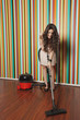 Happy young woman cleaning hardwood floor using vacuum cleaner