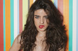 Foto: Portrait of a sensuous young woman biting lips against colorful striped background Portrait of a sensuous young woman biting lips against colorful striped background