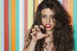 Foto: Portrait of a sensuous young woman gesturing against colorful striped background Portrait of a sensuous young woman gesturing against colorful striped background