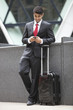 Photo: Young Indian businessman with luggage bag using cell phone Young Indian businessman with luggage bag using cell phone